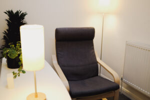 An empty counselling chair in a quietly lit therapy room.