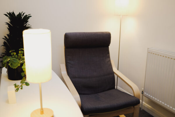 An empty counselling chair in a quietly lit therapy room.
