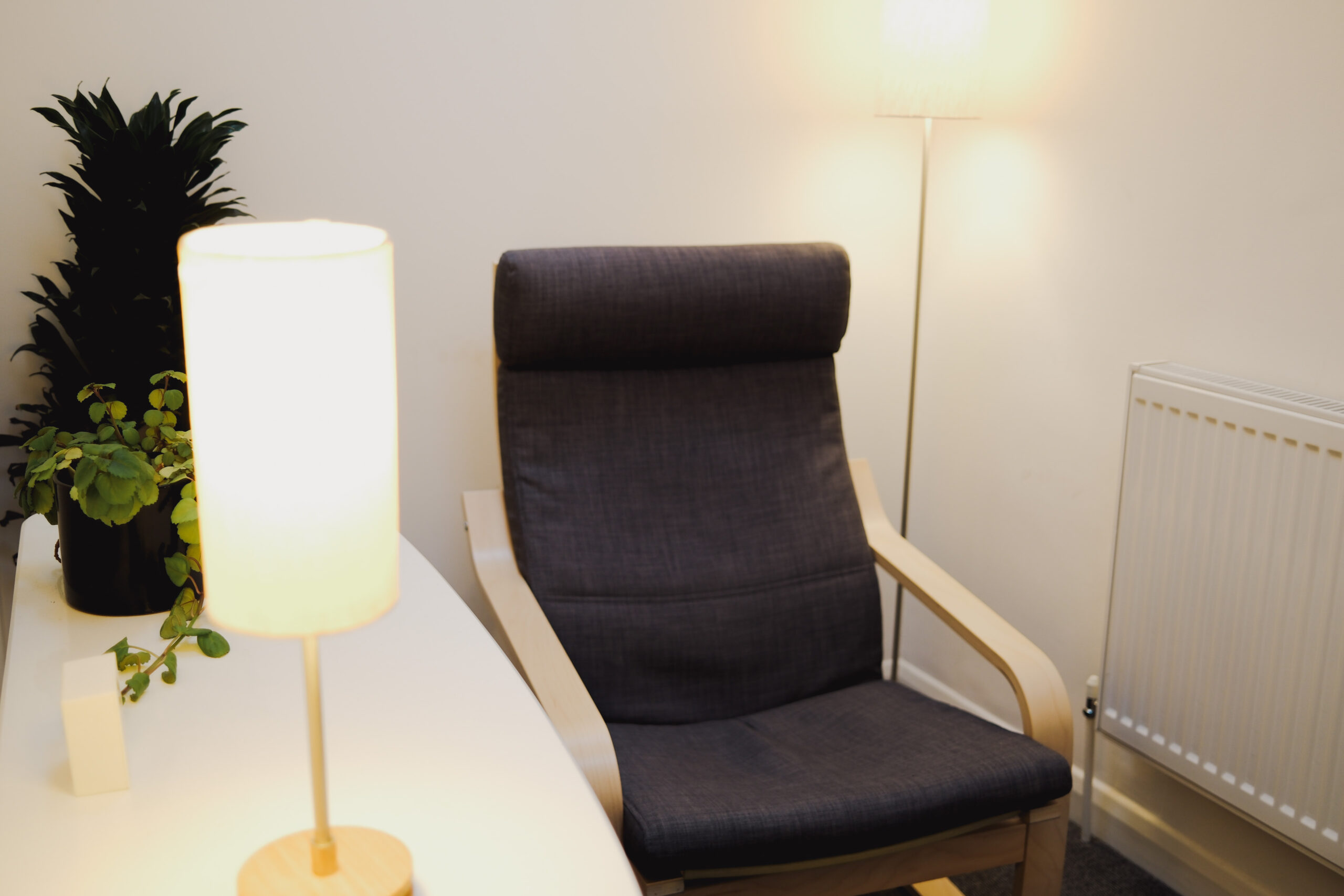 An empty counselling chair in a quietly lit therapy room.