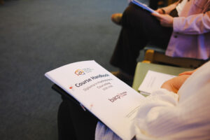 Close-up of a trainee holding the Diploma in Psychodynamic Counselling course handbook, BACP-accredited, during a welcome session.